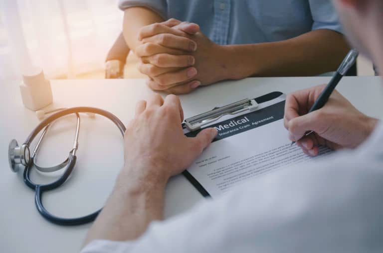Doctor filling out insurance form for rehab